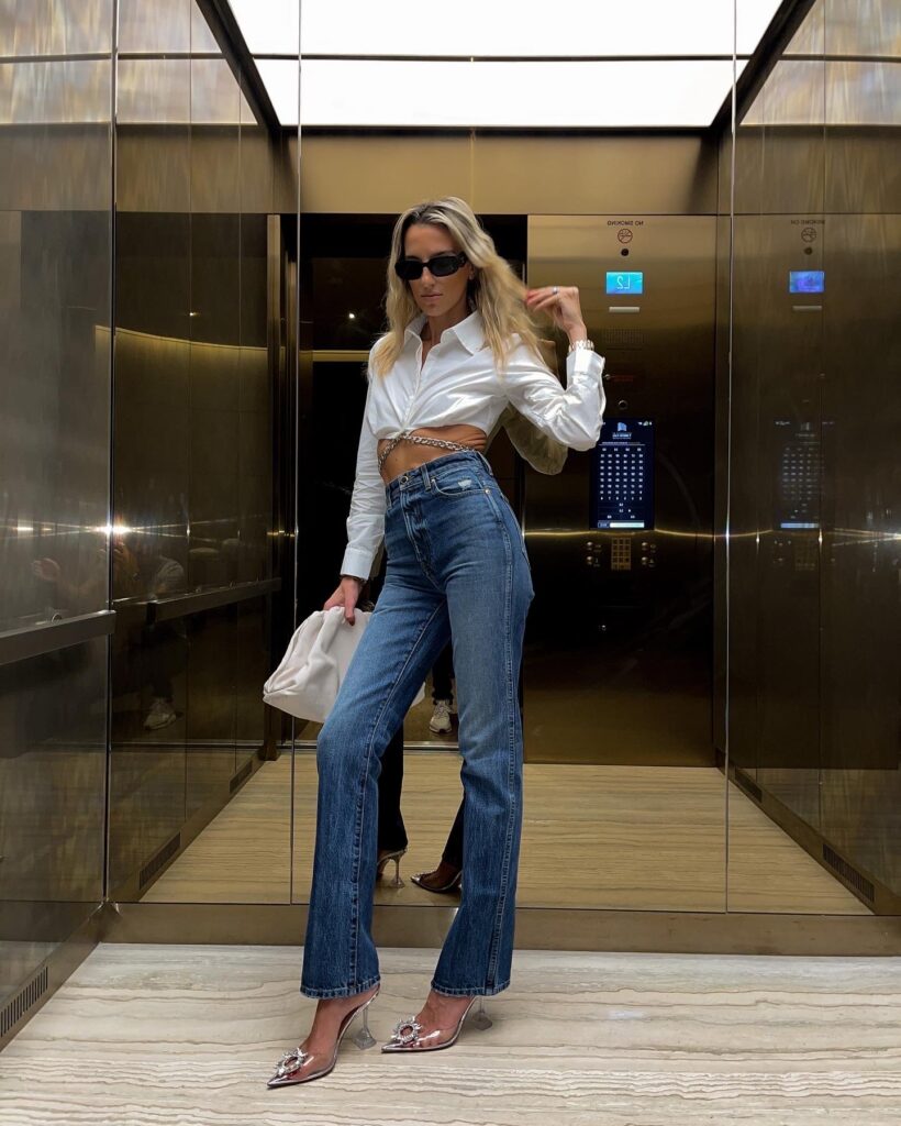 khaite jeans, khaite danielle jeans, khaite denim, the high altitude shirt, FWRD, bottega veneta chain ring, amina muaddi heels, crystal embellished pumps, the pouch clutch, bottega veneta clutch, prada sunglasses